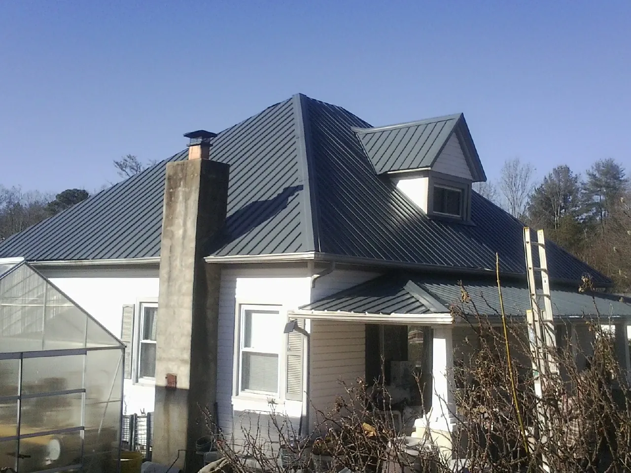 Dark blue standing seam metal roof on a white farmhouse with dormer — Slate & Tile Roof Repair by Roofing Brothers in Fairdale