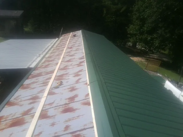 Old rusted panels beside newly installed green metal roofing — Wind Damage Roof Repair by Roofing Brothers in Fairdale