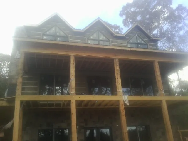 Dormers and porch framing on a large log home under construction — Roof Coating work by our crew in Fairdale