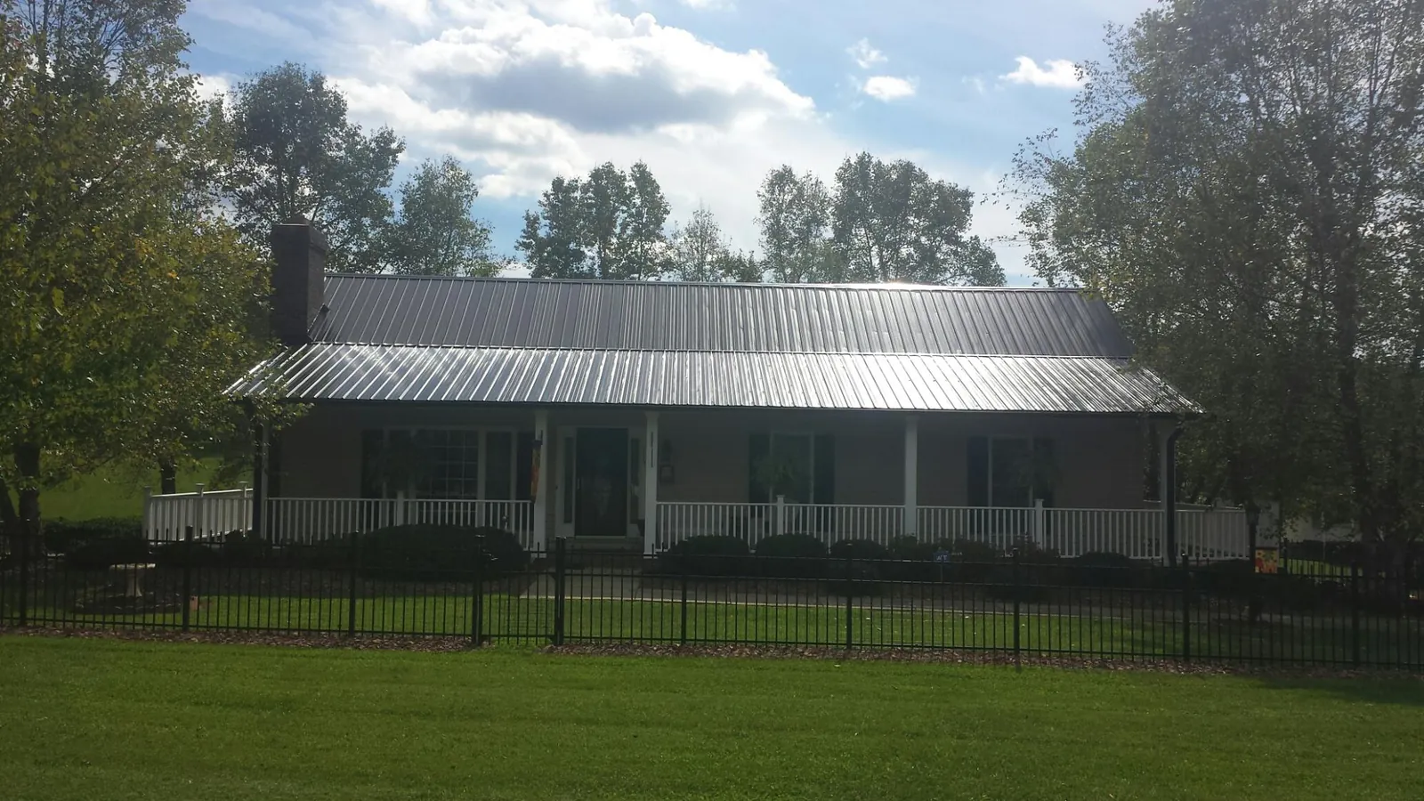 Gray metal roof on a brick ranch with a full width front porch — Gutter Guard Installation work by our crew in Fairdale