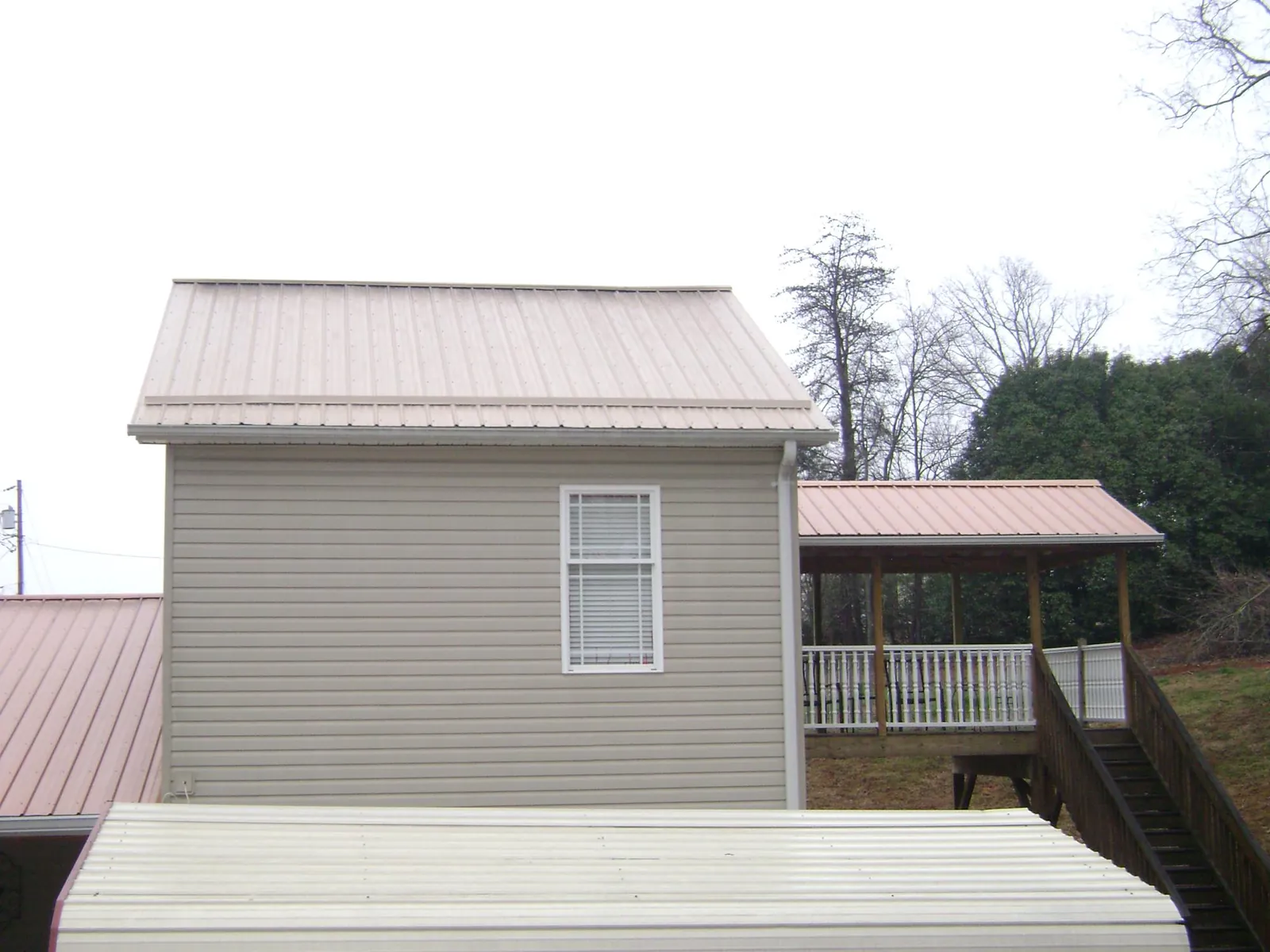 Tan metal roofs on a two story addition and attached porch, from a Roof Replacement job in Fairdale