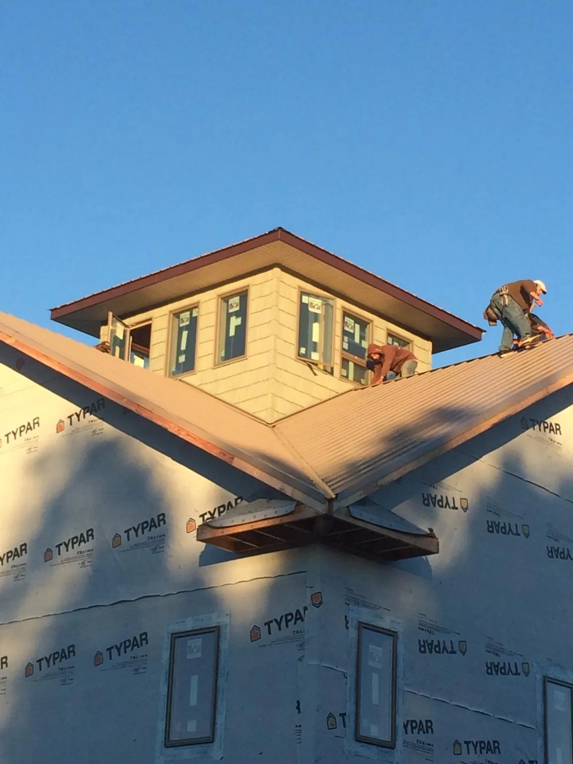 Roofers working around a rooftop cupola on a new metal roof at sunset — Roof Waterproofing in Fairdale by Roofing Brothers